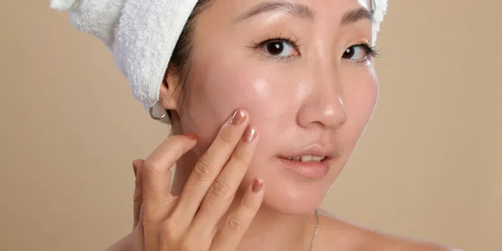 Face of young woman touching her flawless skin