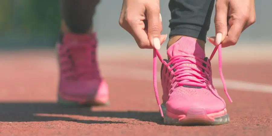 Vrouwelijke sportfitnessloper maakt zich klaar om buiten te gaan joggen op de atletiekbaan