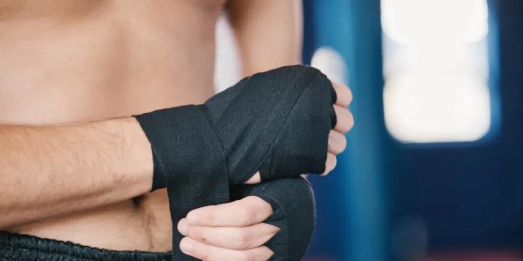 Fitness, boxing and man wrap hands with abdomen closeup in gym for training