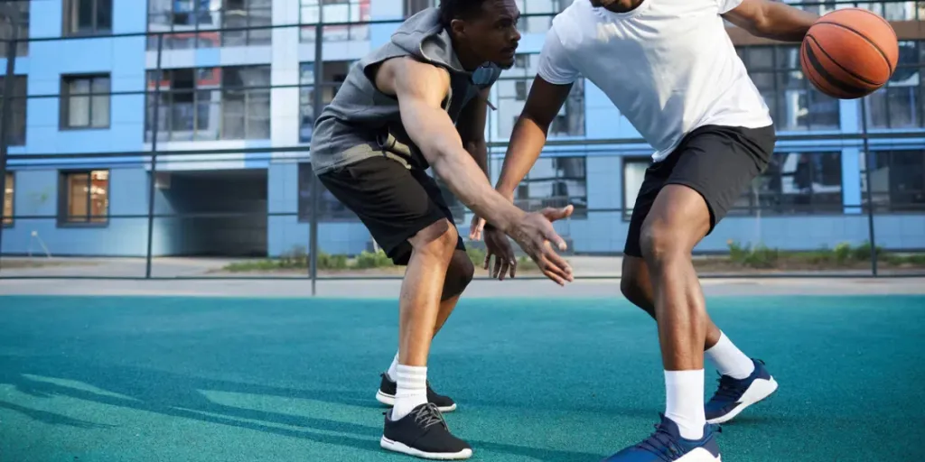 Full length action shot of two muscular African man playing basketball outdoors