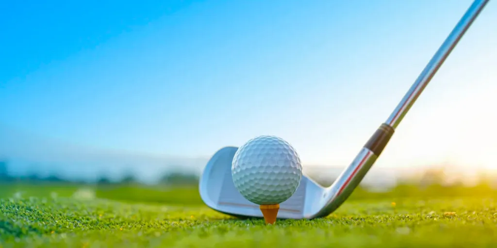 Golf clubs and golf balls on a green lawn in a beautiful golf course with morning sunshine