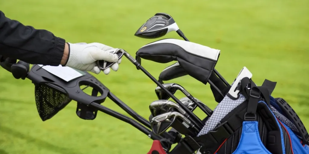 Jogador de golfe tira um taco de golfe da bolsa para atirar a bola