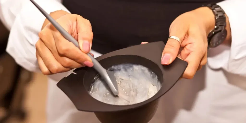 Manos de peluquero mezclando tinte para el cabello en un recipiente