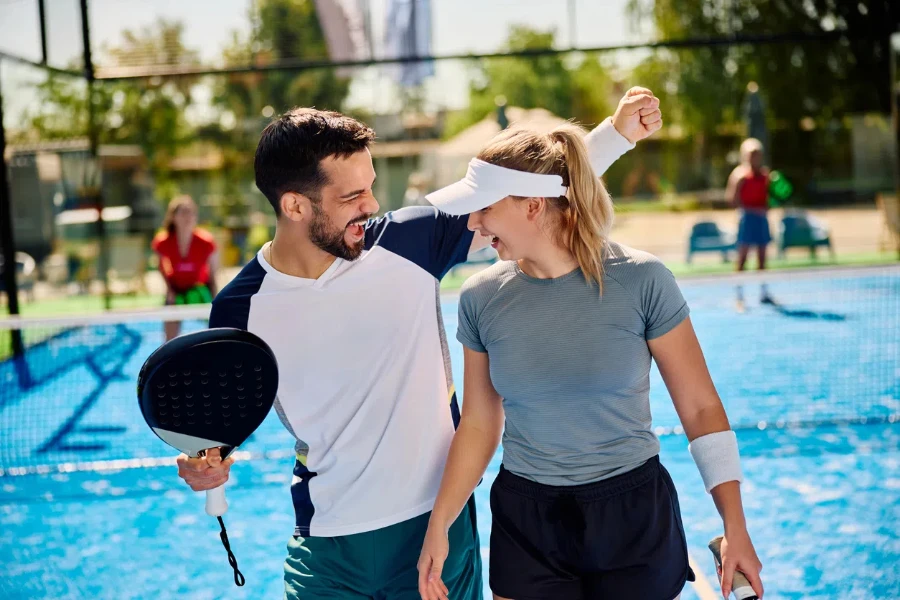 Jugadores de pádel felices celebrando la victoria tras jugar dobles en una cancha al aire libre