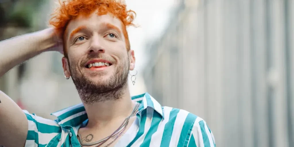 Hipster Gay man in a striped shirt standing on the street and smiling