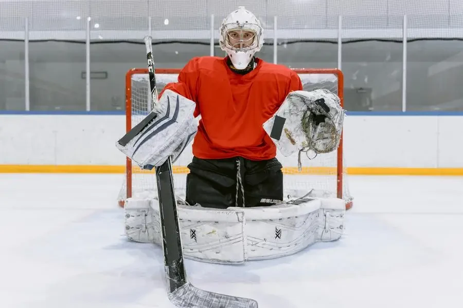 Hockey goalie in red jersey, guarding the net during an indoor game