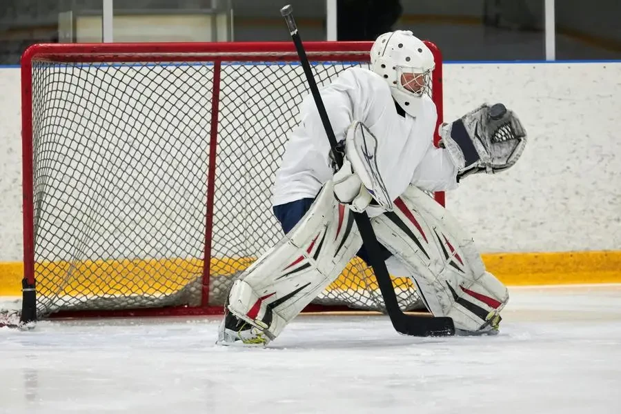 Ice hockey goalie in full gear defending the goal during a game on an indoor rink