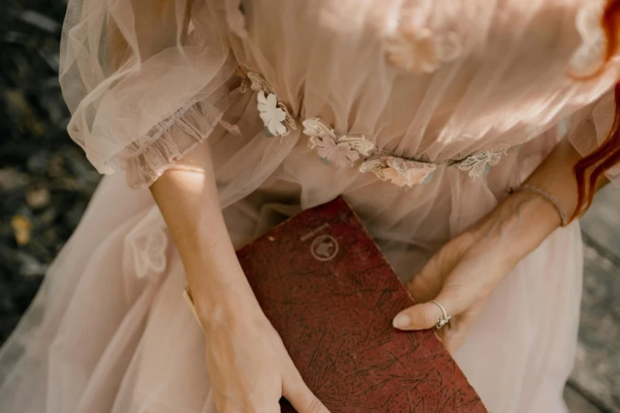 Lady in beige sheer midi dress holding a brown book