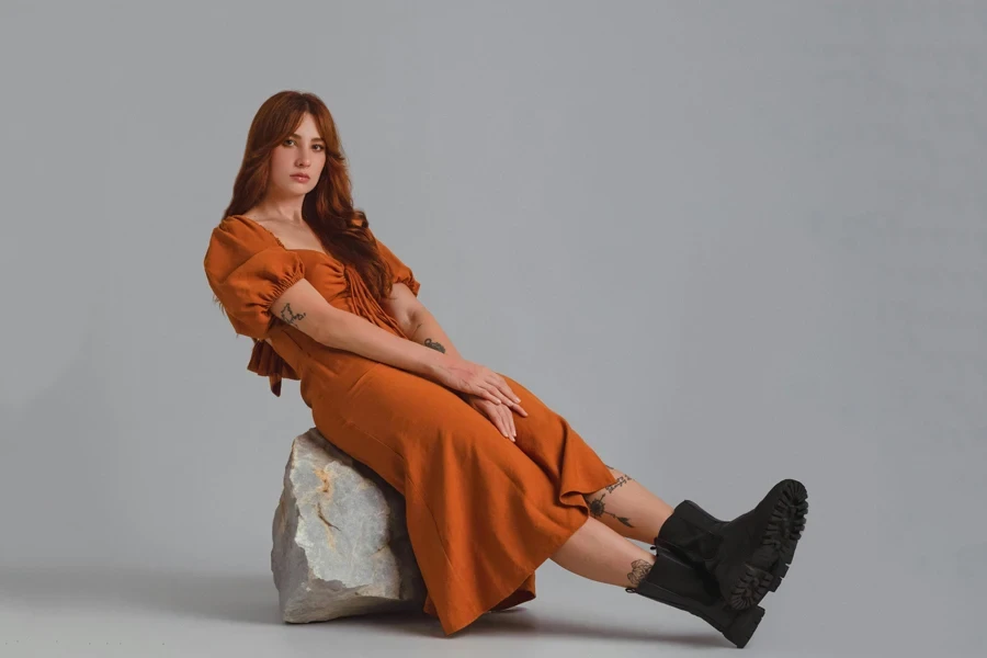 Lady on burnt orange cotton dress sitting on a rock