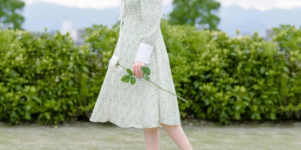 Lady on floral white and green gown holding a flower