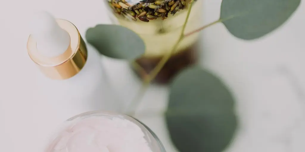 Minimalist skincare display featuring creams and oils with eucalyptus leaves