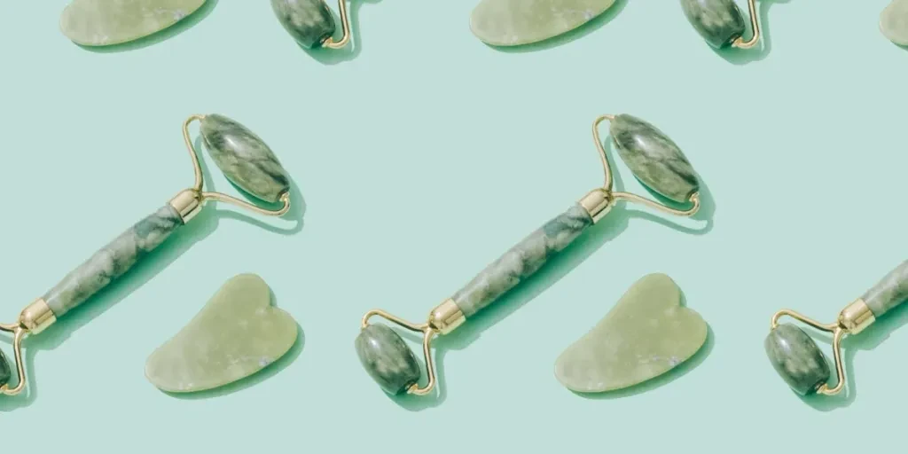 Pattern made with jade gua sha tool and facial roller on pastel green background