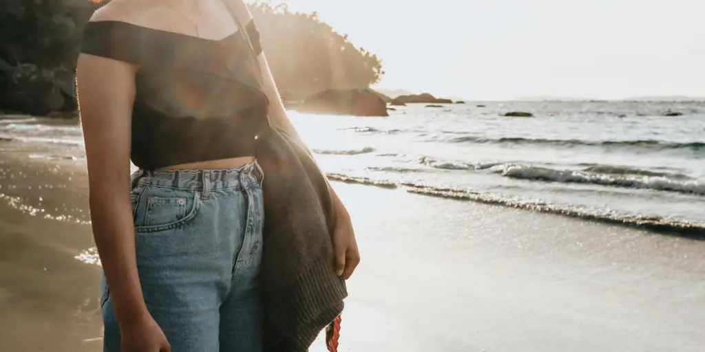 Person Stands On Sandy Beach Looking Out To The Water