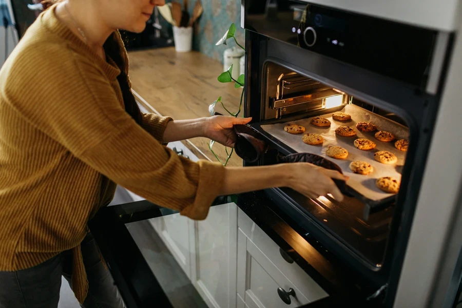 Persona sacando galletas de un horno convencional