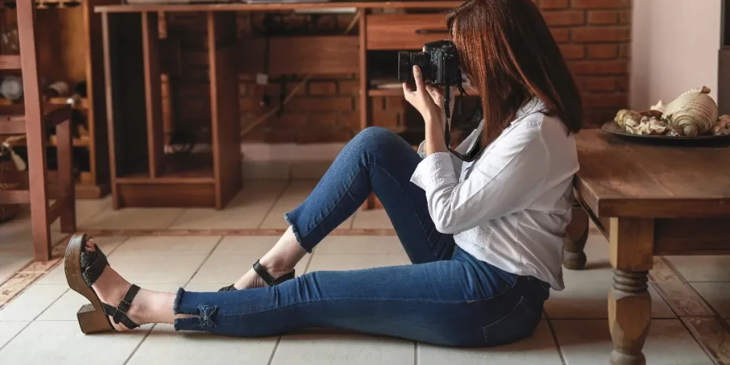 Photographer Sits On Floor Holding A Camera To Their Face