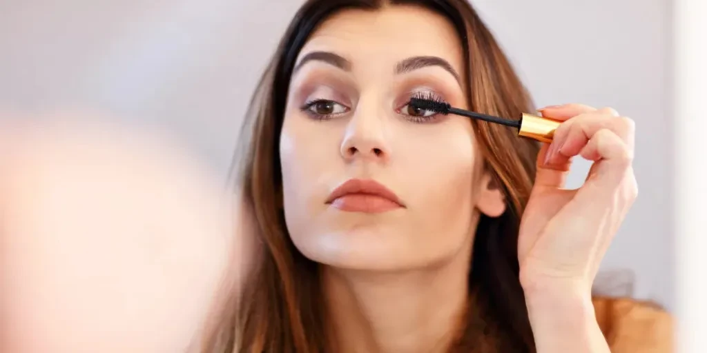 Picture of young woman doing make-up while looking at the mirror in bathroom