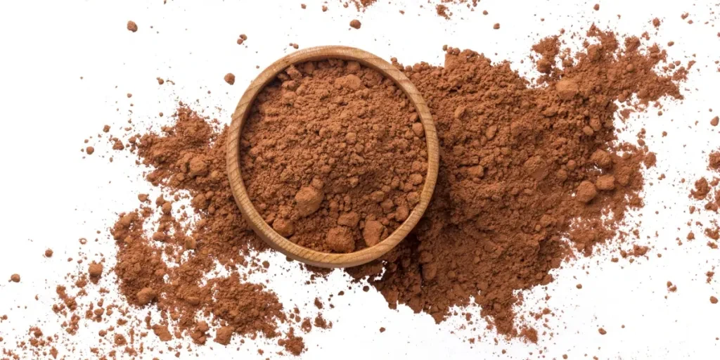 Pile of cocoa powder in wooden bowl isolated on white background