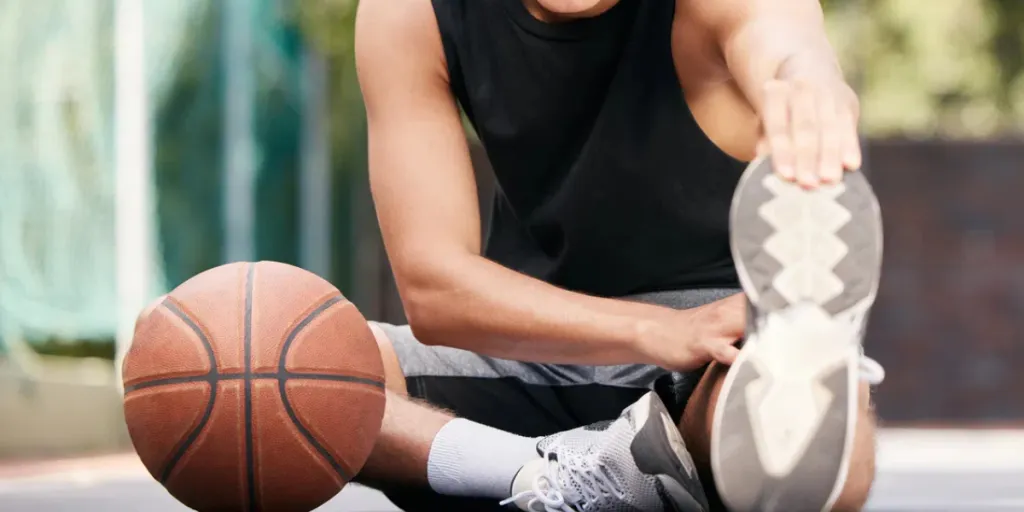 Retrato, baloncesto y hombre estirando las piernas para mayor flexibilidad.