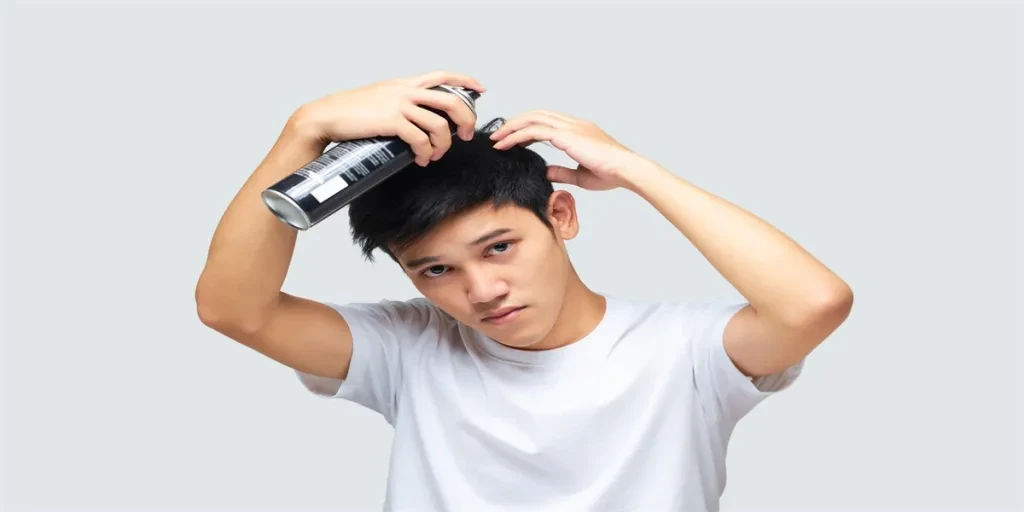 Portrait of a handsome young Asian man wearing a white t-shirt using his hand styling their hair