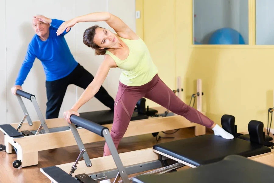 Portrait of woman performing set of pilates exercises on reformer during group workout for adults in fitness studio