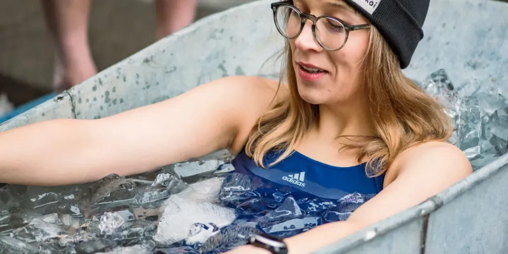 Pretty girl or woman wearing a hat, smiling and ice bathing in the cold water