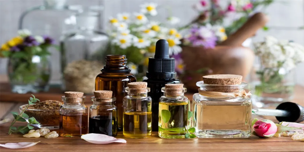 Selección de aceites esenciales con diversas hierbas y flores de fondo.