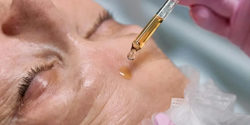 Senior woman receiving a facial serum treatment in a spa setting