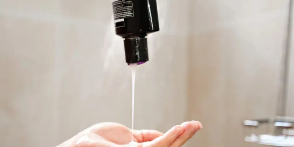 Shampoo is poured from the bottle into the palm of the hand