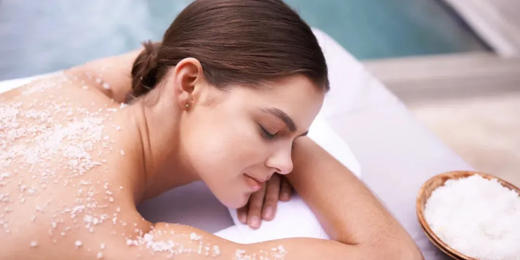 Shot of a young woman enjoying a salt exfoliation treatment