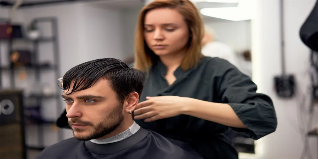 Hombre elegante sentado en la barbería Estilista Peluquero Mujer cortando