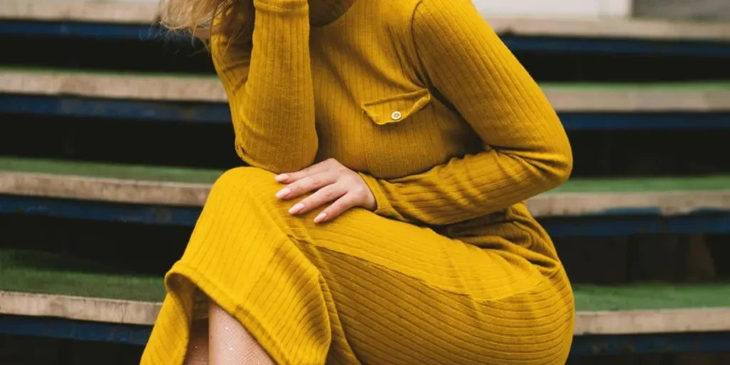 Mulher estilosa em vestido amarelo e óculos escuros posando em degraus. Retrato de moda moderna