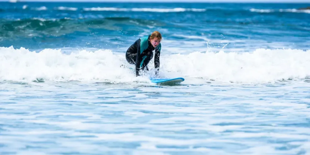 Surfer girl surfing with surfboard on waves in Atlantic ocean