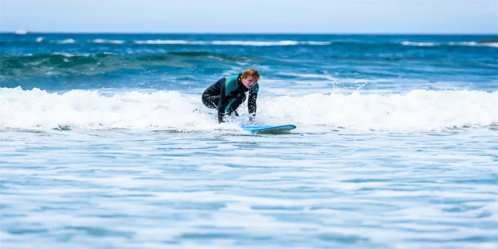 Surfer girl surfing with surfboard on waves in Atlantic ocean