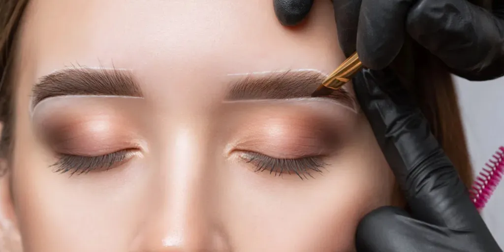 The make-up artist does Long-lasting styling of the eyebrows of the eyebrows and will color the eyebrows