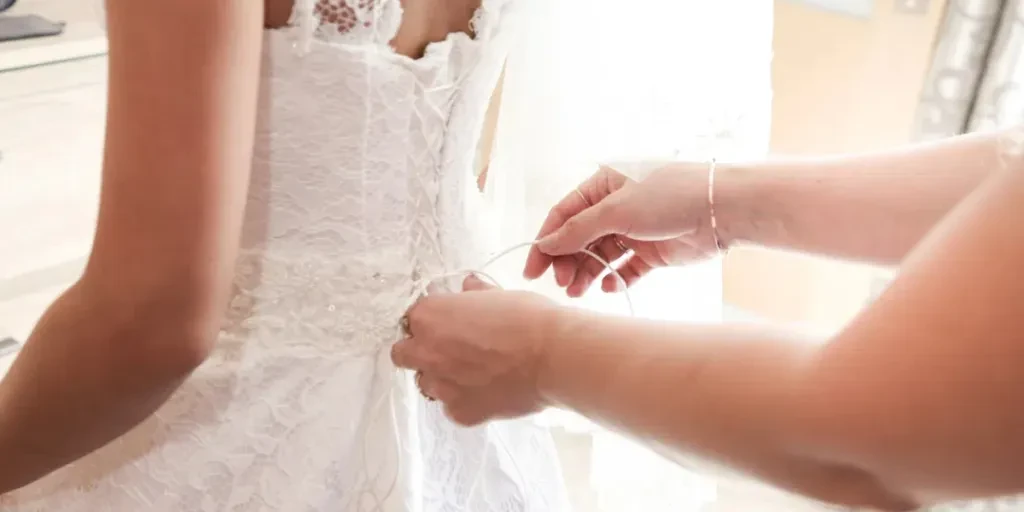 Les mains de la femme nouent la robe de la mariée dans le dos