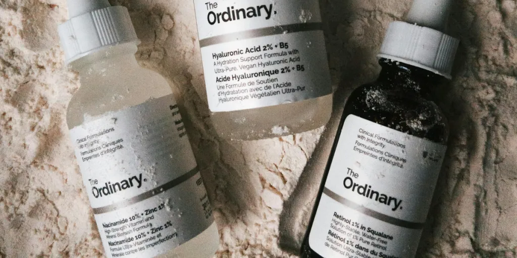 Three dropper bottles of The Ordinary serums displayed on a powdery surface