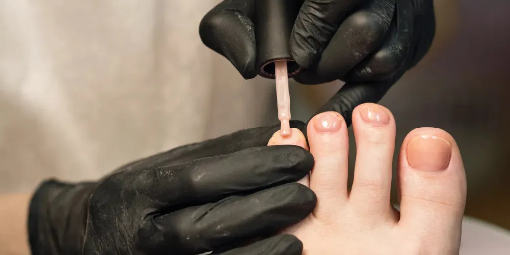 Applicazione di base traslucida. Pedicure da vicino in un salone spa alla moda