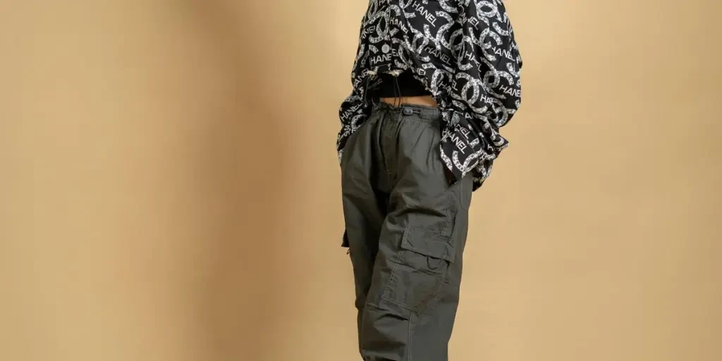 Jeune femme branchée posant dans un pantalon cargo élégant et des lunettes de soleil dans un décor de studio