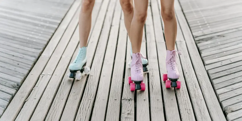 Dos personas patinando sobre una pasarela de madera, mostrando patines de colores