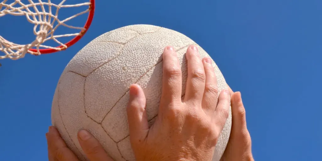 Dos jugadores de netball compiten por el balón debajo de un aro de netball