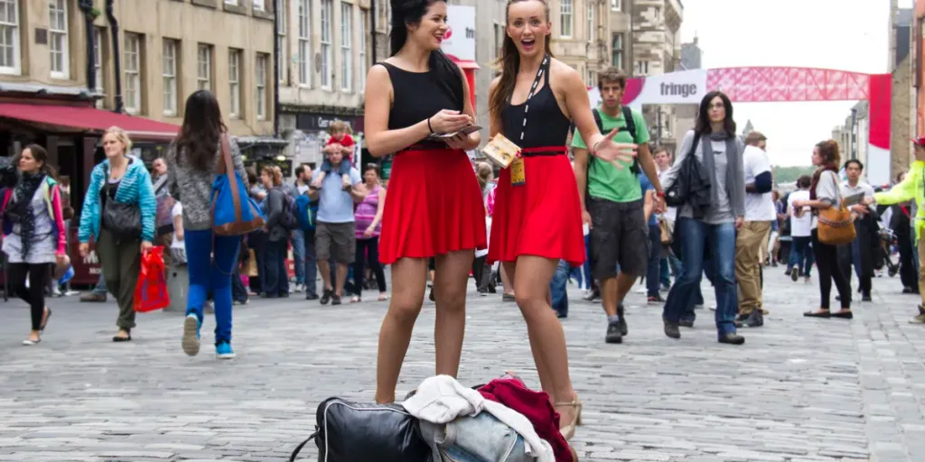 Two unidentified girls hand out flyers on the street at the Edinburgh Festival Fringe