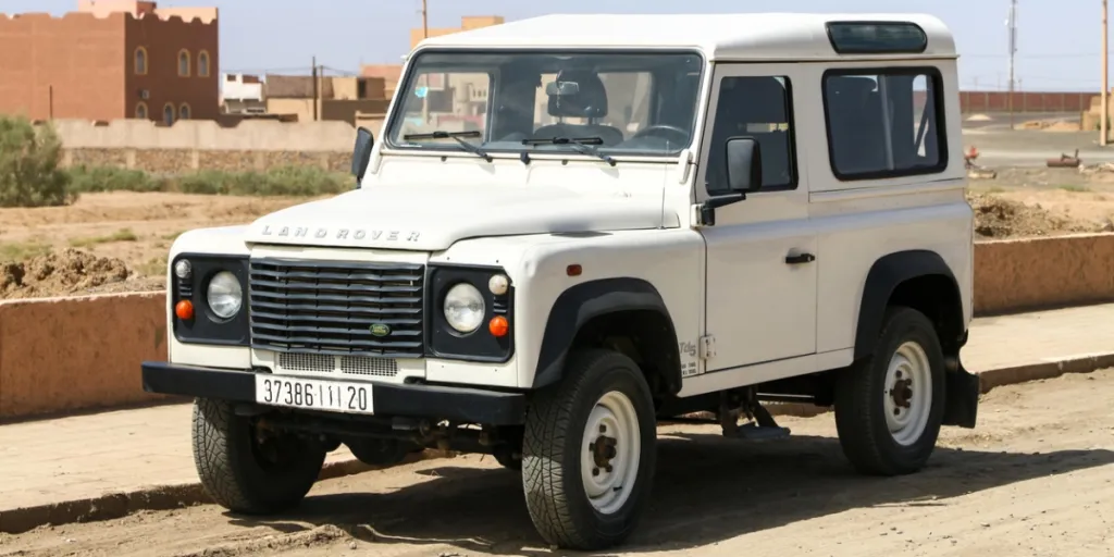 Land Rover Defender putih di jalan berkerikil