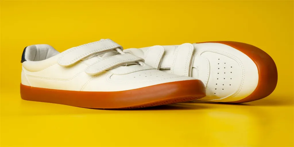 White leather sneakers with advehise fasteners on yellow background close up