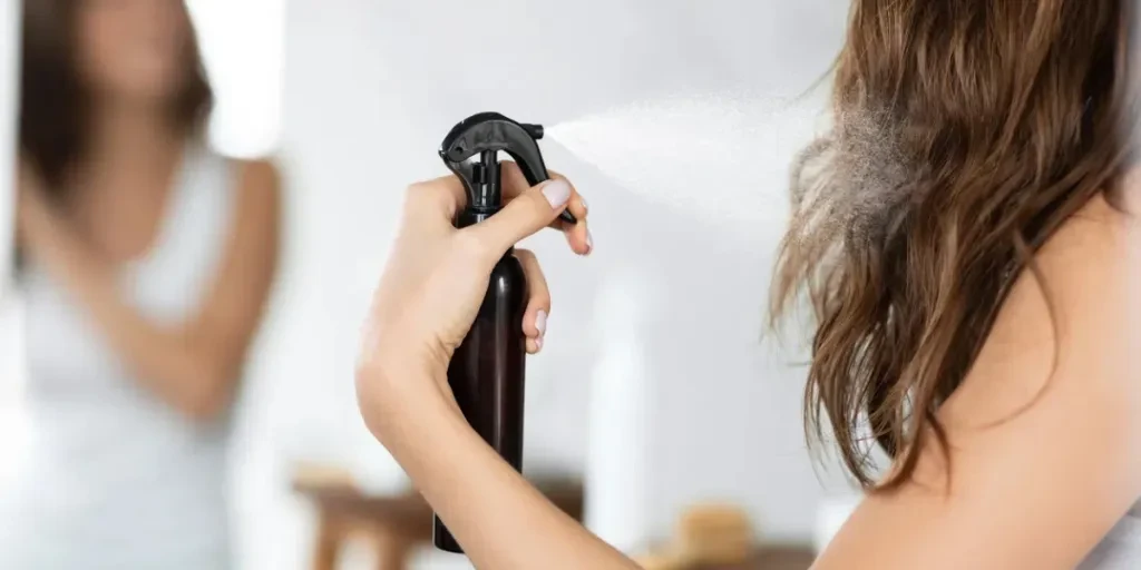 Mujer aplicando laca para el cabello para repararlo