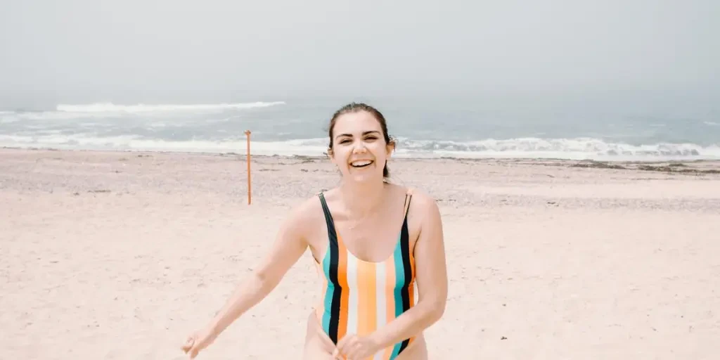 Vrouw loopt naar de camera op een strand