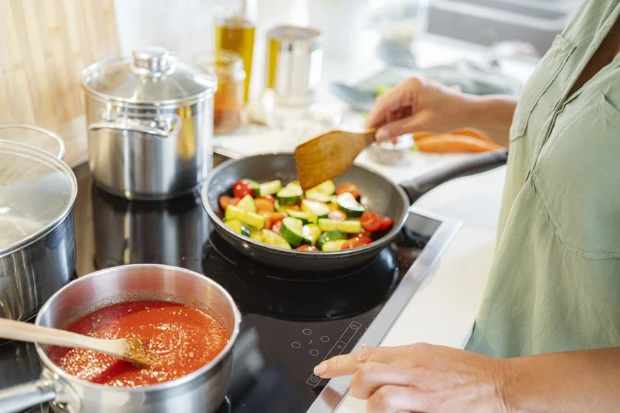 Femme réglant la température d'une cuisinière électrique