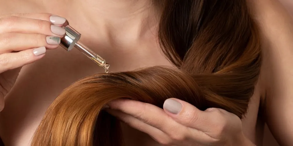 Woman applying hair serum closeup