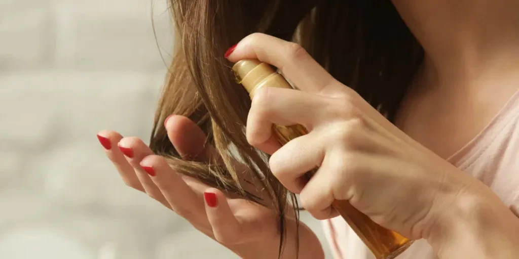 Femme appliquant de l'huile sur les pointes de ses cheveux