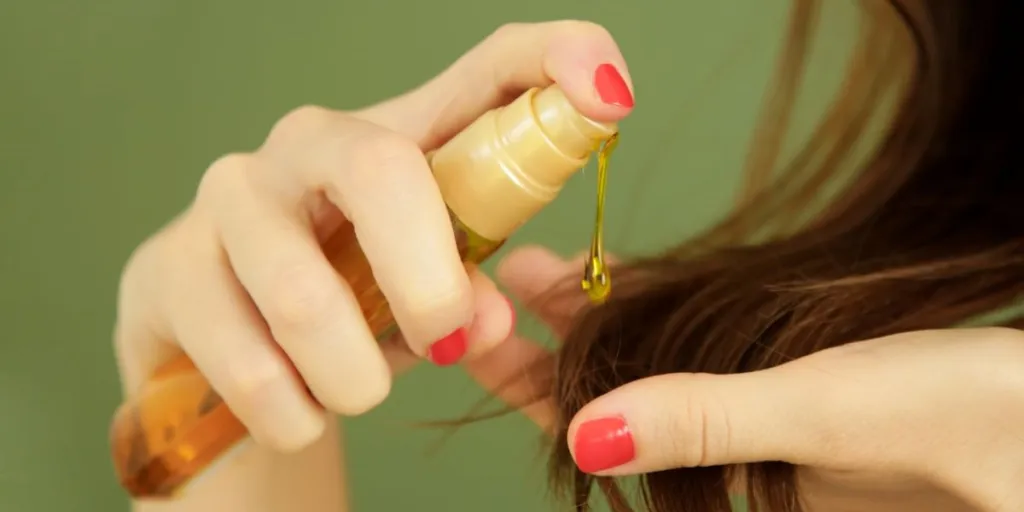 Woman applying oil on hair ends, split hair tips, dry hair or sun protection concept