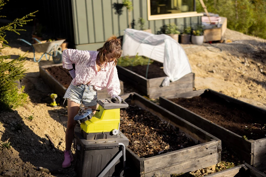 Femme remplissant un tas de compost à l'aide d'un broyeur à compost